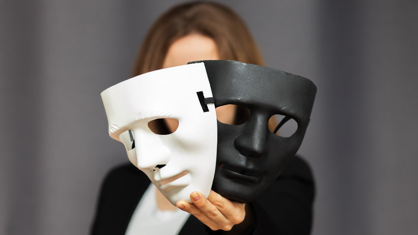 Personality, Identity, and Crime Eine Person hält eine weiße und eine schwarze Maske in ihrer Hand vor sich