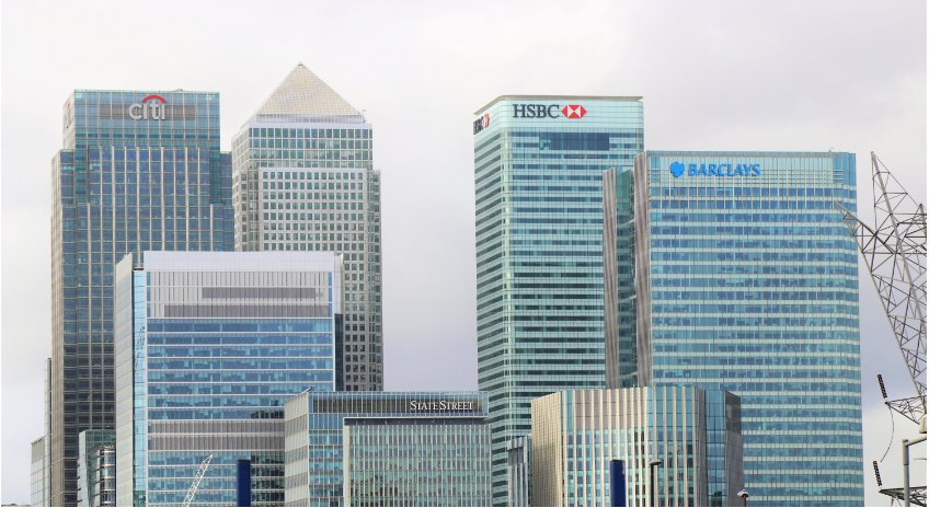 Glasfassaden von Hochhäusern in einer Finanzmetropole. Die Hochhäuser tragen Logos von Banken.