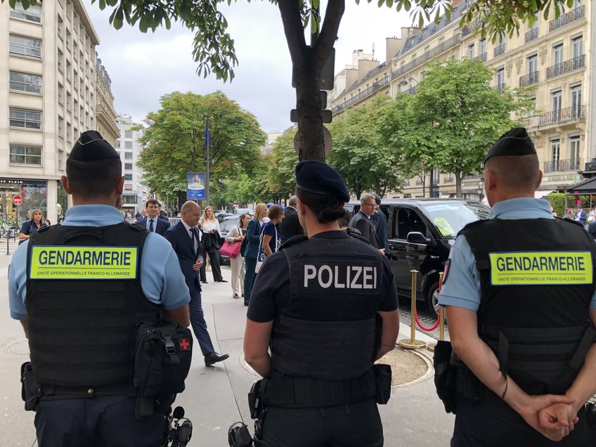 Aktuelle Herausforderungen transnationaler Sicherheitskooperation. Eine deutsch-französische Perspektive Polizisten/Gendarmerie auf der Straße, im Hintergrund der Bundeskanzler und weitere Personen